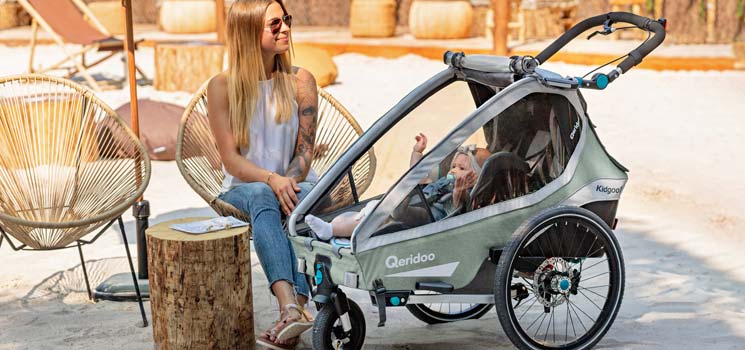 Mutter mit Baby in Qeridoo Babyschale im Kindersportwagen Mutter mit Baby in Qeridoo Babyschale im Kindersportwagen