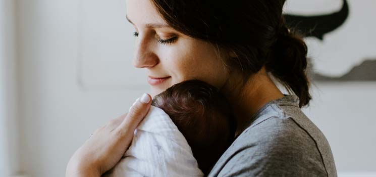 Mutter behütet Kind im Arm