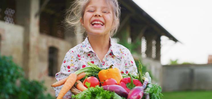 Mädchen mit Korb gefüllt mit Obst und Gemüse voller Vitamine