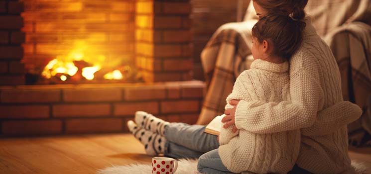 Mutter mit Tochter vor Kamin