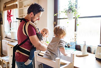 Vater verteilt in der Küche Aufgaben an die Kinder und spült Geschirr Vater verteilt in der Küche Aufgaben an die Kinder und spült Geschirr