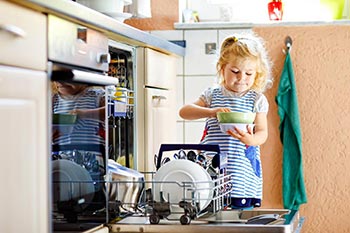 Kind räumt den Geschirrspüler aus Kind räumt den Geschirrspüler aus