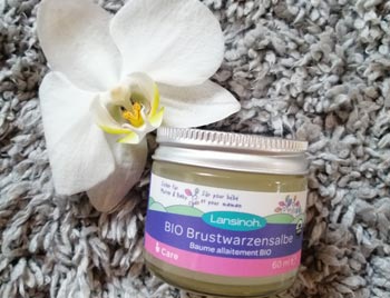 Lansinoh Brustwarzensalbe Tiegel mit Orchidee auf Teppich