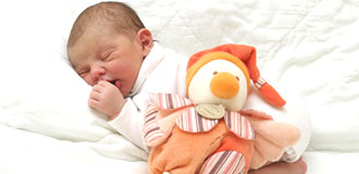 Neugeborenes liegt entspannt im Bett nach erfolgreicher Geburtsbegleitung durch die Hebamme