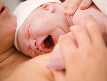 Neugeborenes gähnt am Körper der Mutter im Anschluss an eine natürliche Geburt Neugeborenes gähnt am Körper der Mutter im Anschluss an eine natürliche Geburt