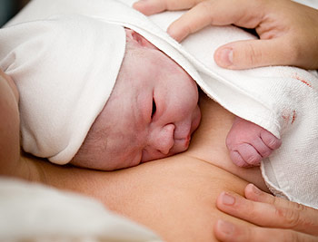 Durch die selbstbestimmte Geburt liegt Neugeborenes glücklich auf dem Körper der Mutter Durch die selbstbestimmte Geburt liegt Neugeborenes glücklich auf dem Körper der Mutter