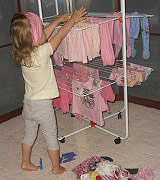 Mädchen hängt Kkleidung auf nach der Wäsche mit Persil Sensitive Mädchen hängt Kkleidung auf nach der Wäsche mit Persil Sensitive